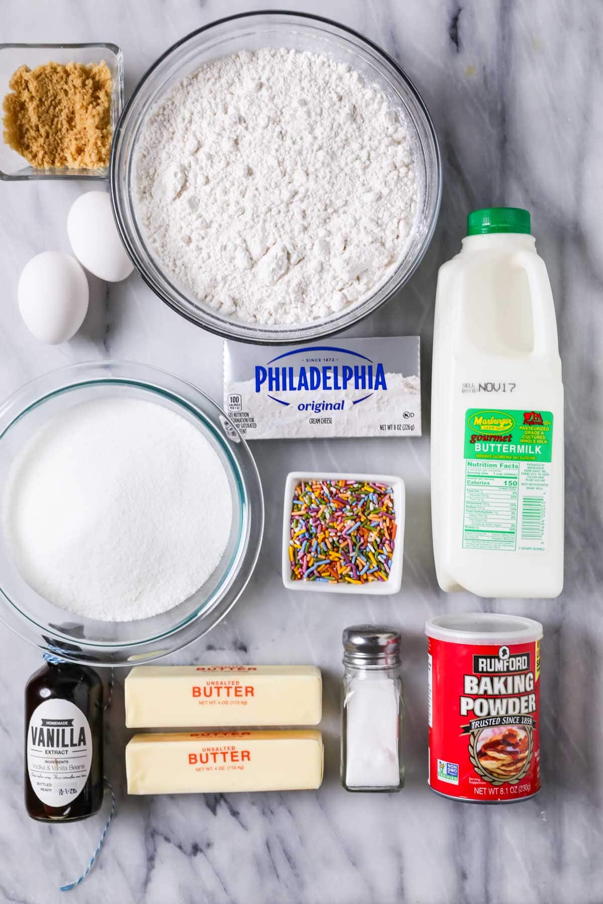 Overhead view of ingredients including buttermilk, sprinkles, cake flour, cream cheese, and more.