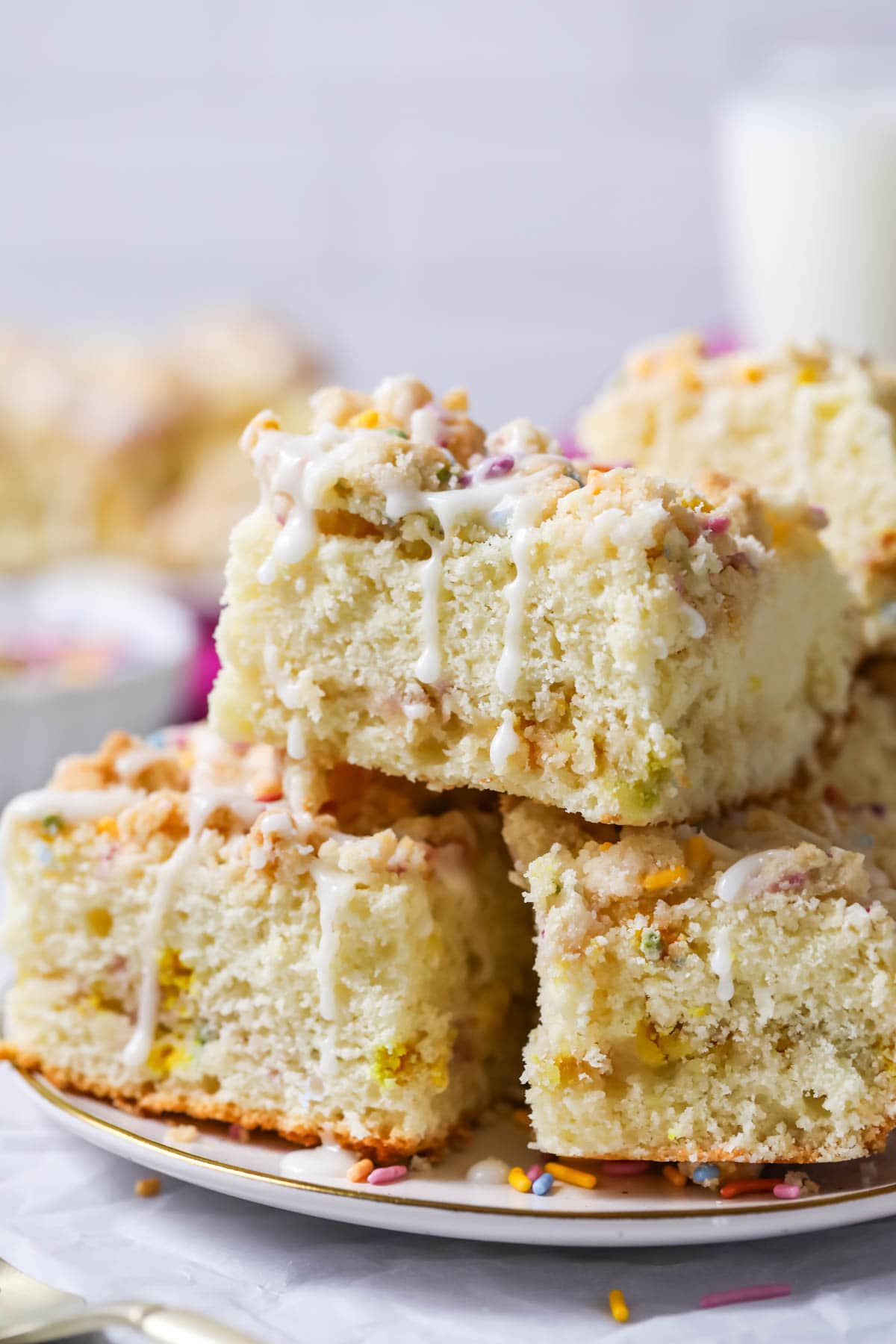 Square slices of crumb cake made with a sprinkle infused topping and vanilla glaze.
