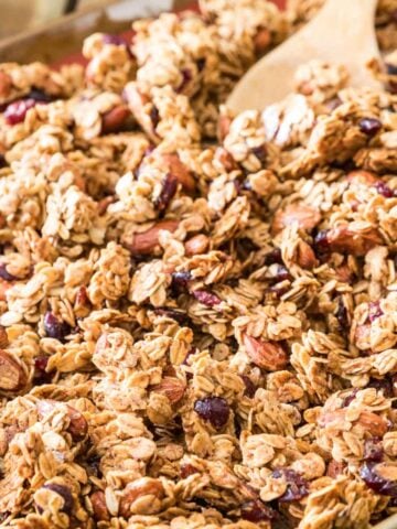 Closeup of the results of this granola recipe; golden granola clusters on baking sheet