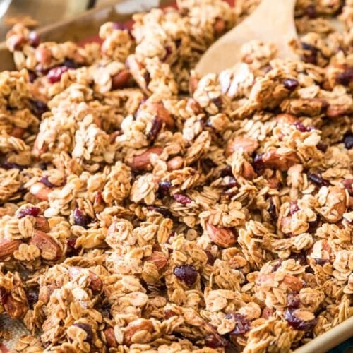 Closeup of the results of this granola recipe; golden granola clusters on baking sheet