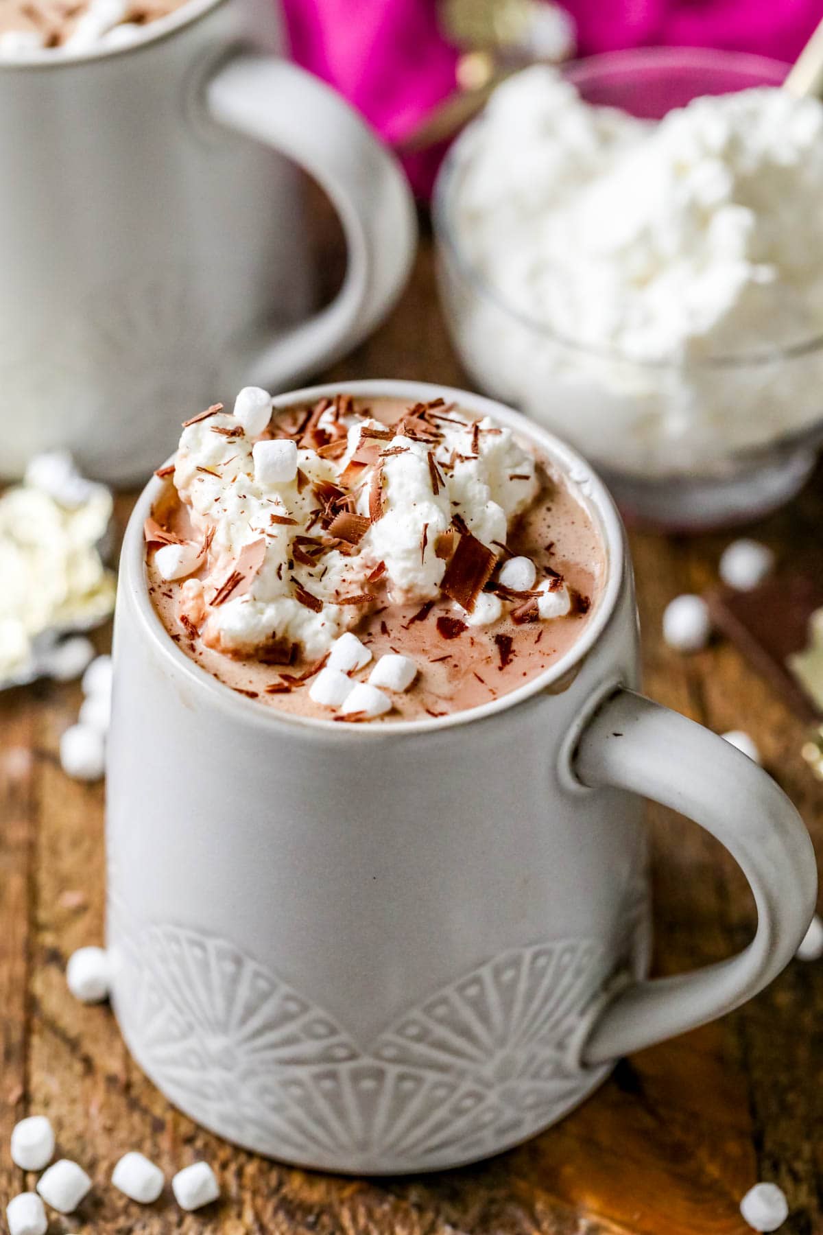 Cup of hot cocoa topped with marshmallows, whipped cream, and chocolate shavings.