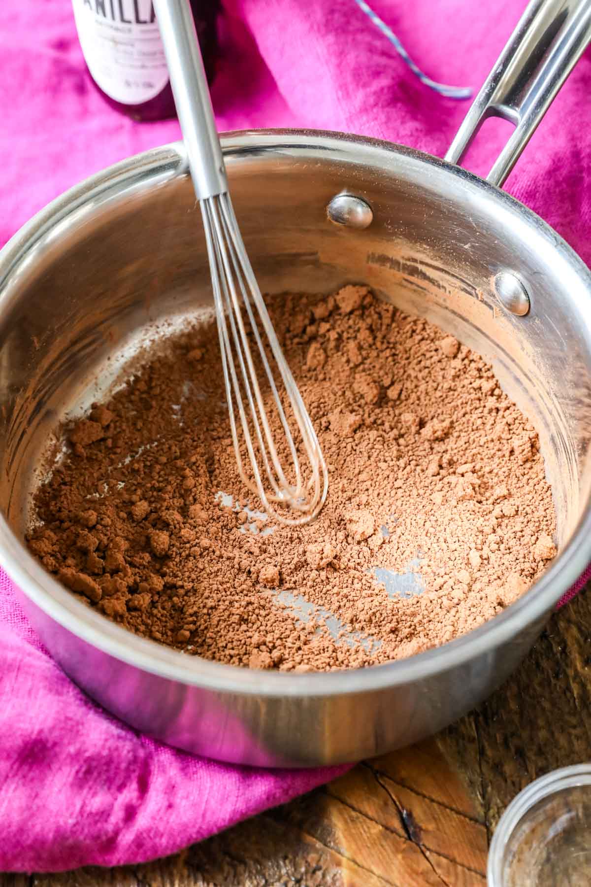 Cocoa powder, brown sugar, and salt being whisked together in a pot.