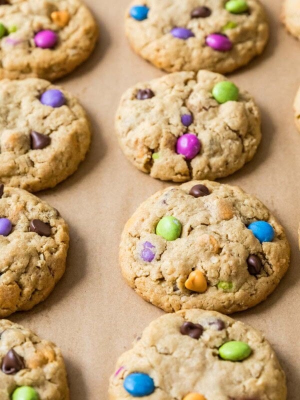 Rows of monster cookies made with colorful candies on a baking sheet.