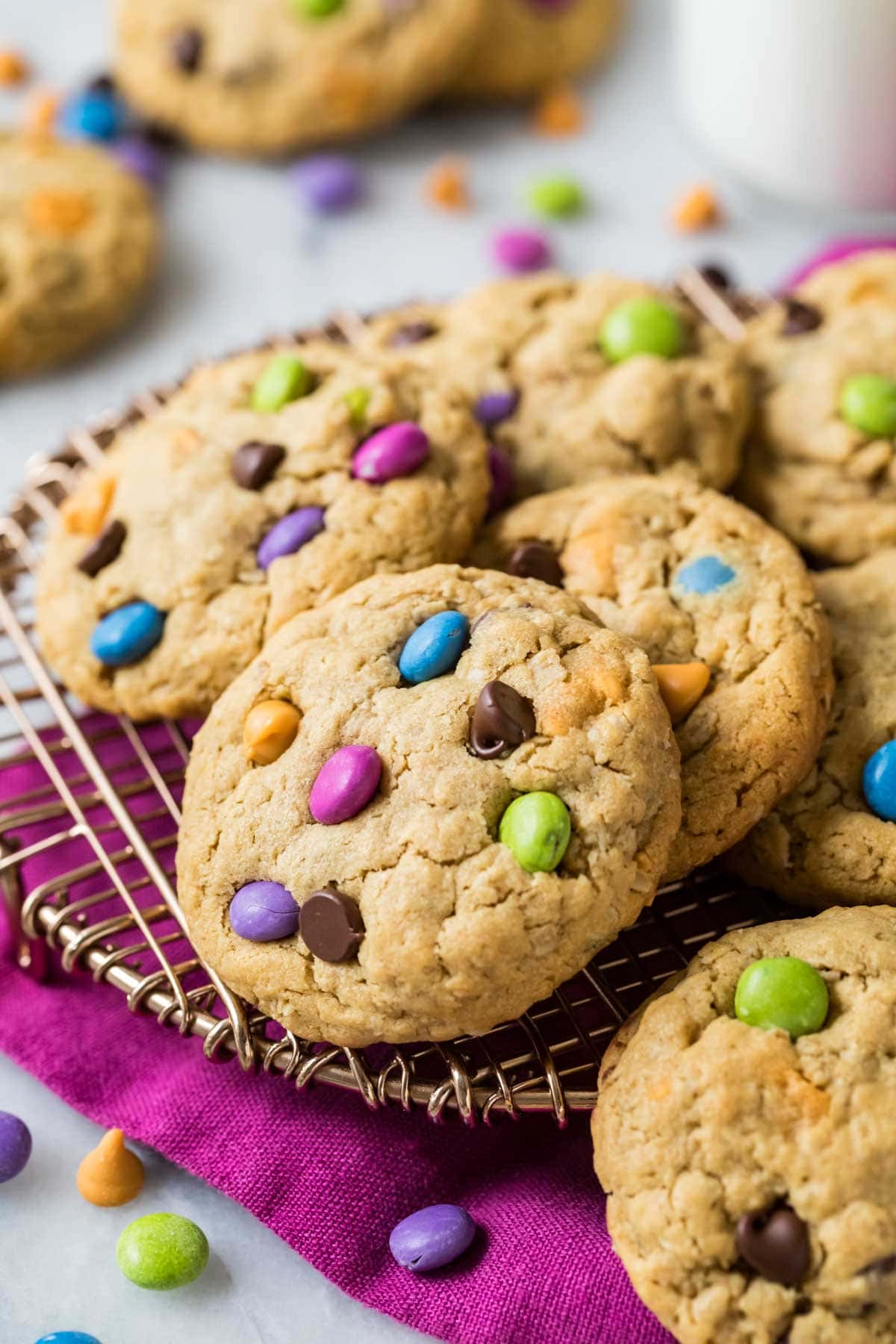 Cookies made with oats, colorful candy coated chocolate, and peanut butter on a cooling rack.