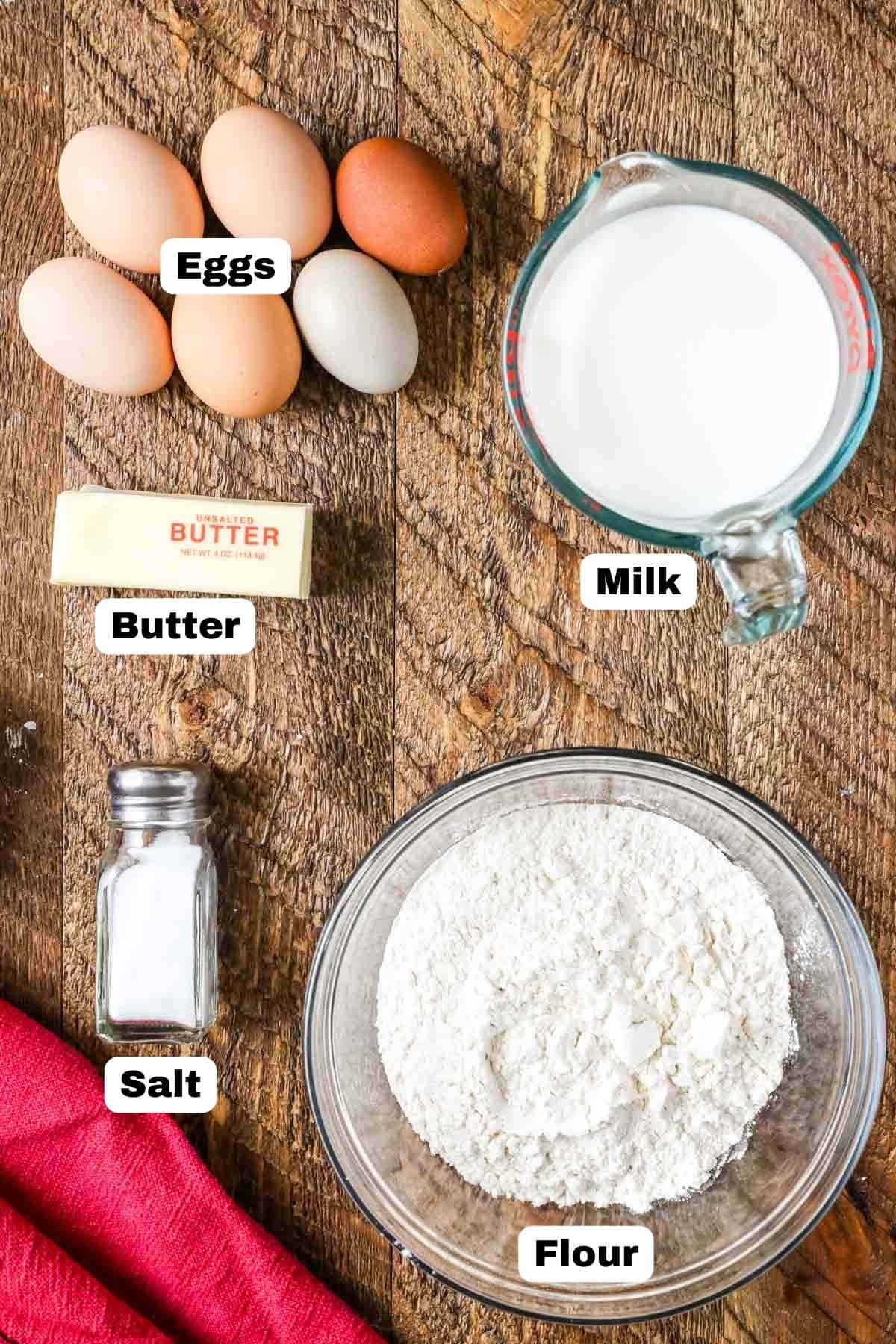 Overhead view of labelled ingredients including eggs, milk, flour, butter, and salt.