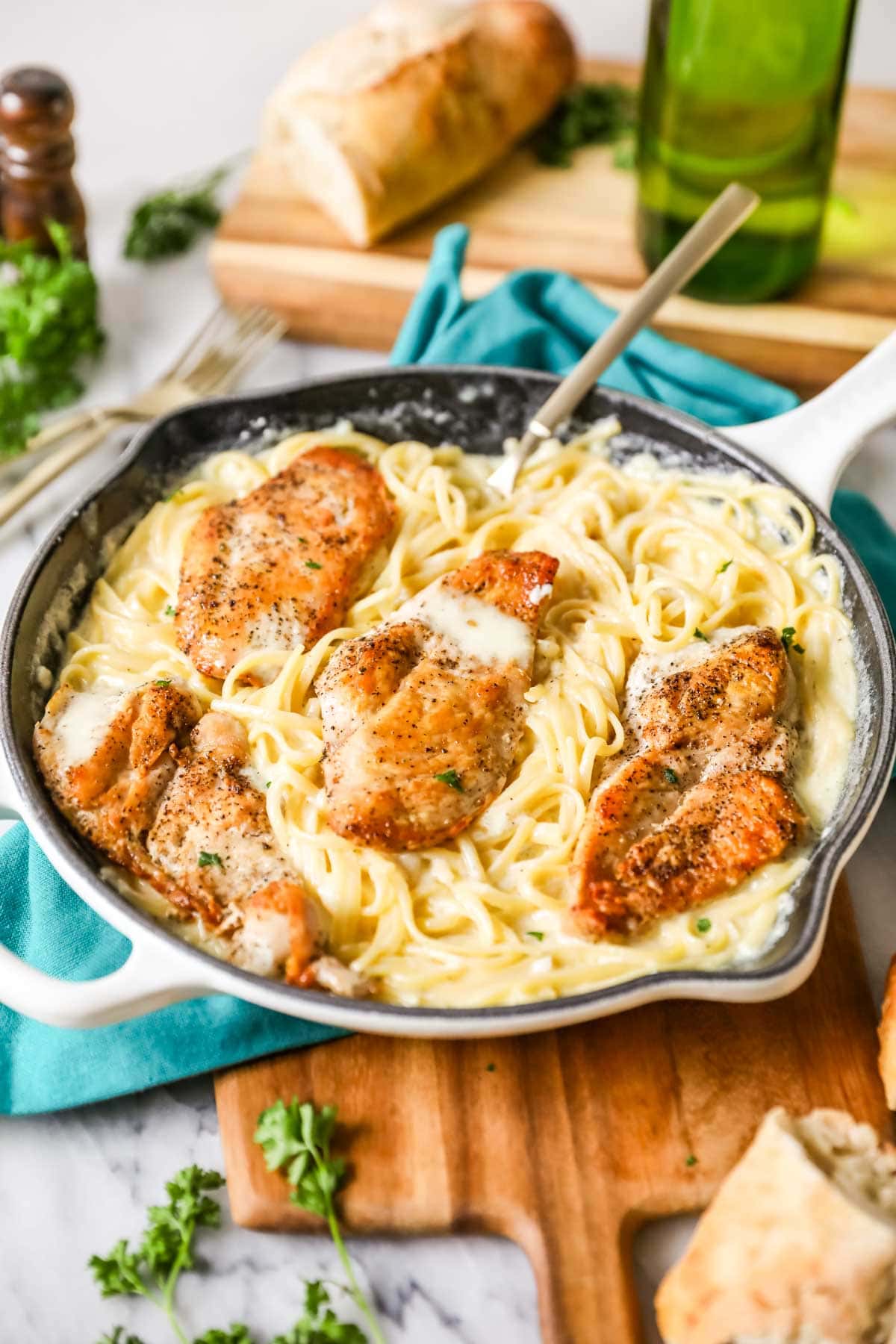 Skillet of pasta with alfredo sauce and seared chicken breasts.