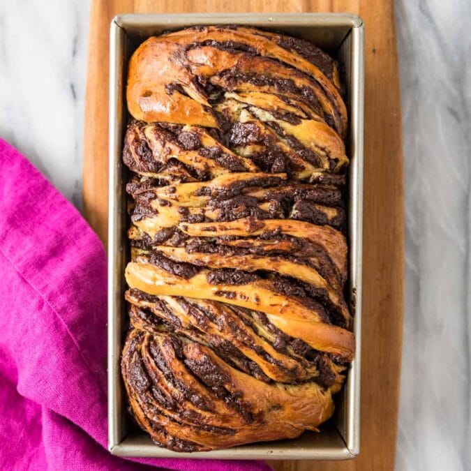 Overhead view of a loaf of chocolate babka in a pan.
