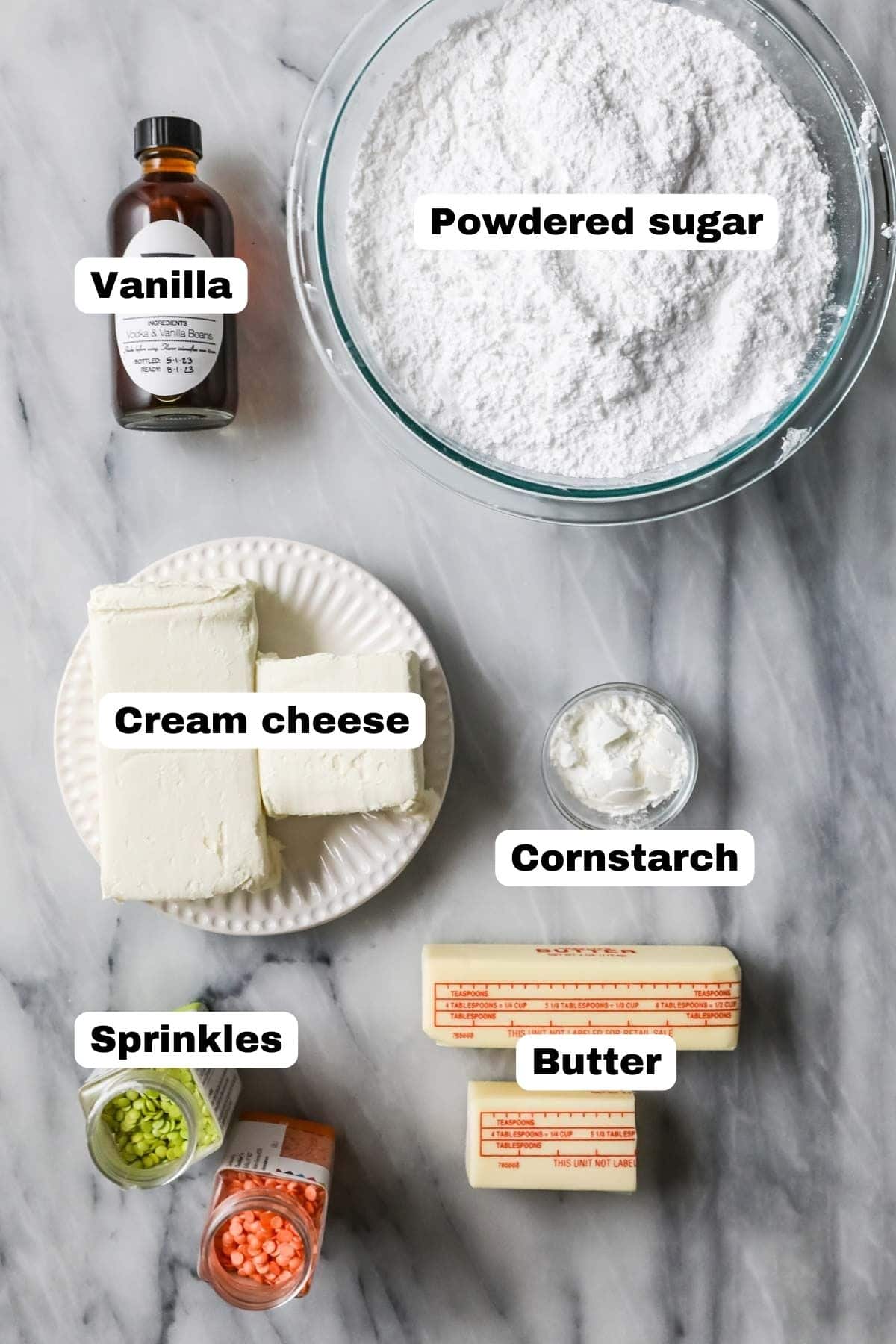 Overhead view of labelled ingredients including powdered sugar, cream cheese, butter, and more.