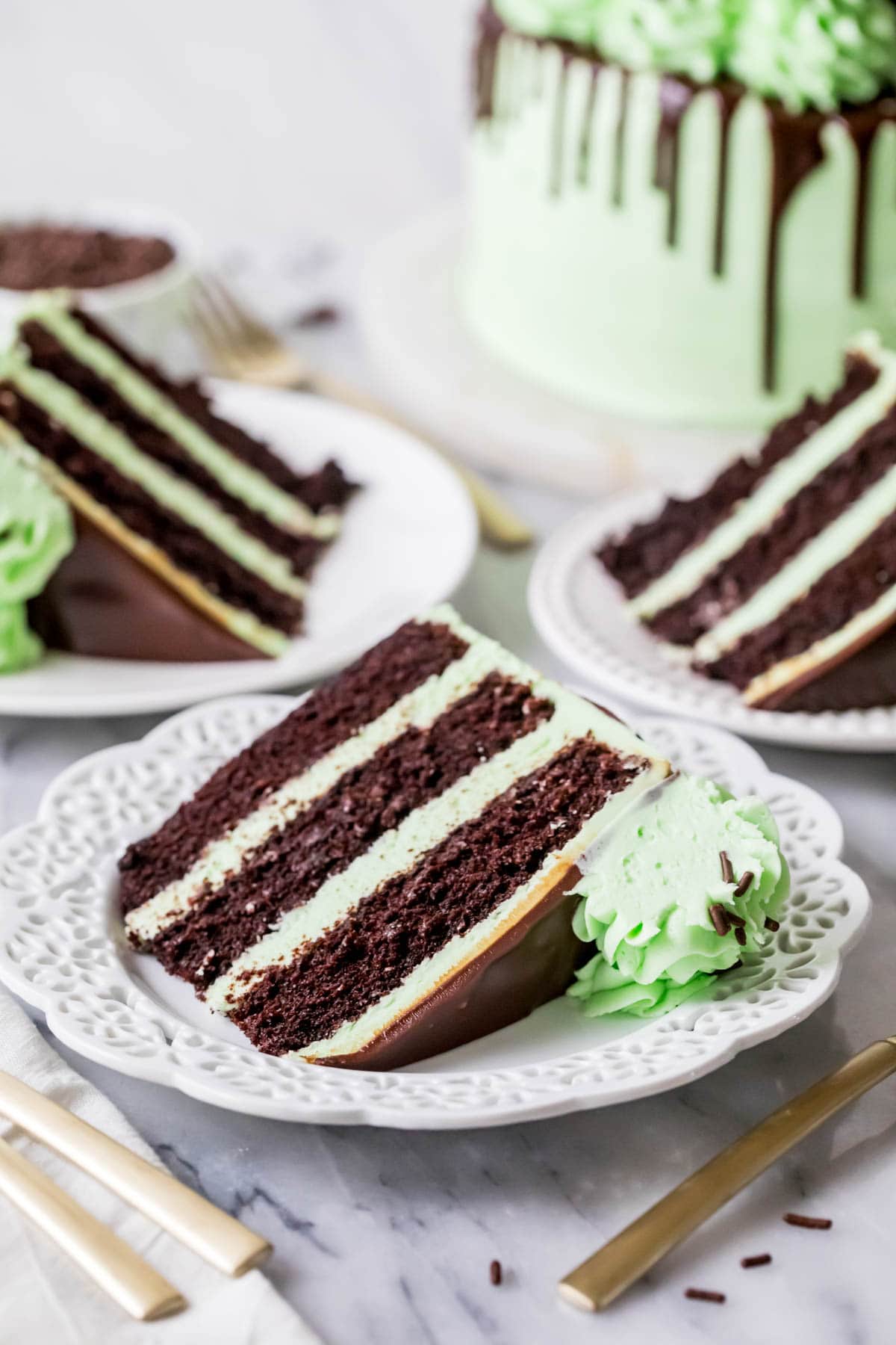 Slices of chocolate cake with mint frosting on white plates.