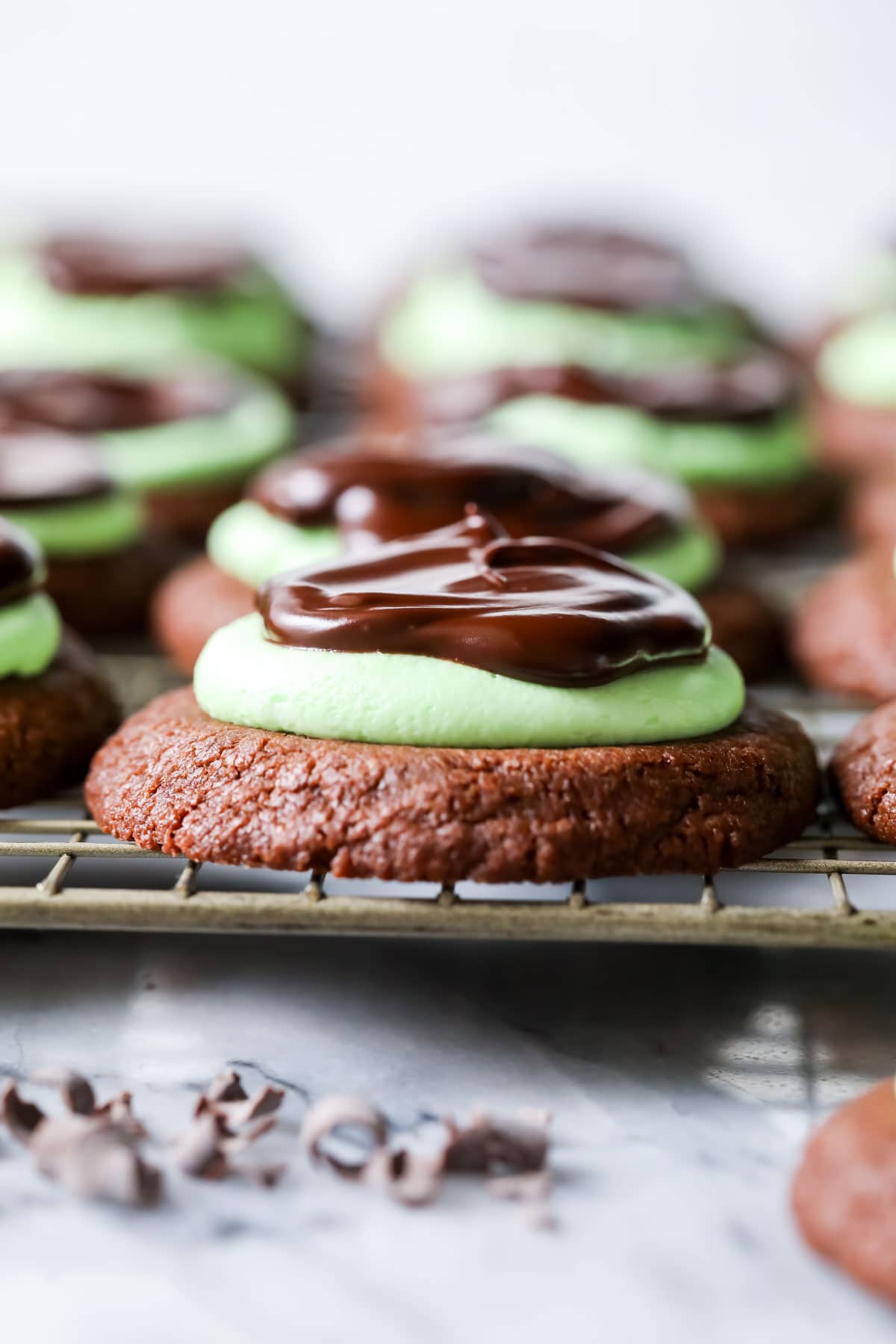 Close up, head-on view of a row of mint chocolate cookies on a cooling rack.