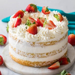 Strawberry shortcake cake decorated with whipped cream frosting and fresh berries.