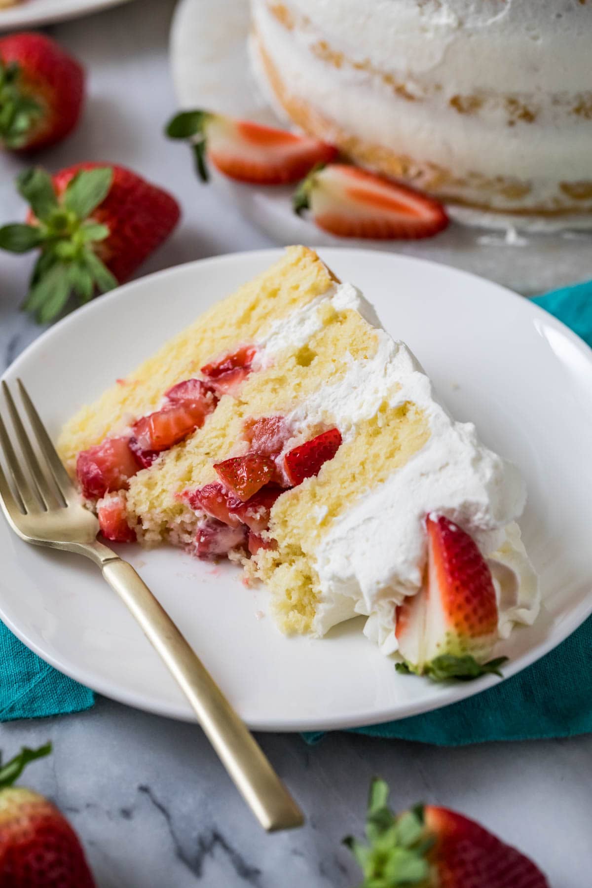 Slice of strawberry shortcake cake with several bites missing on a plate.