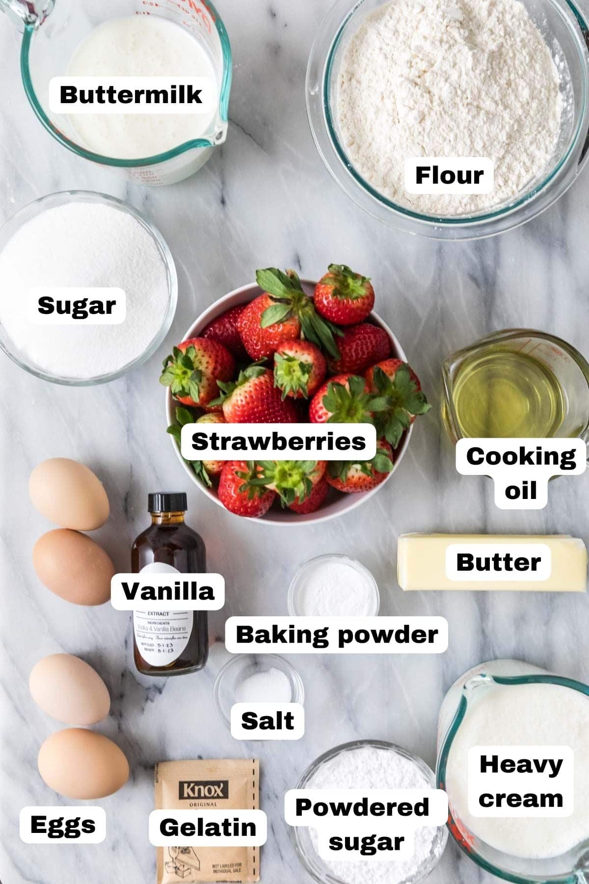 Overhead view of labelled ingredients including strawberries, gelatin, flour, cream, and more.