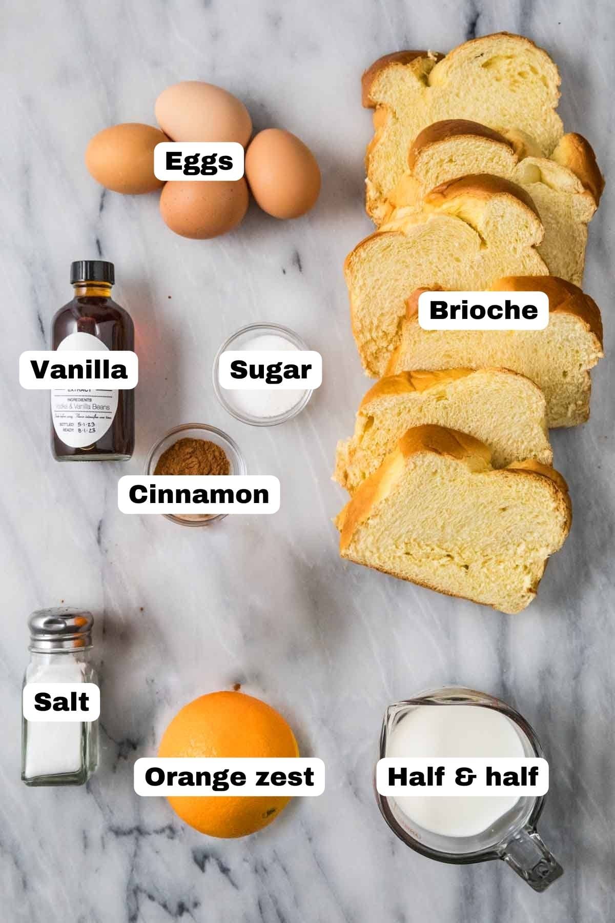 Overhead view of labelled ingredients including brioche, eggs, orange zest, and more.