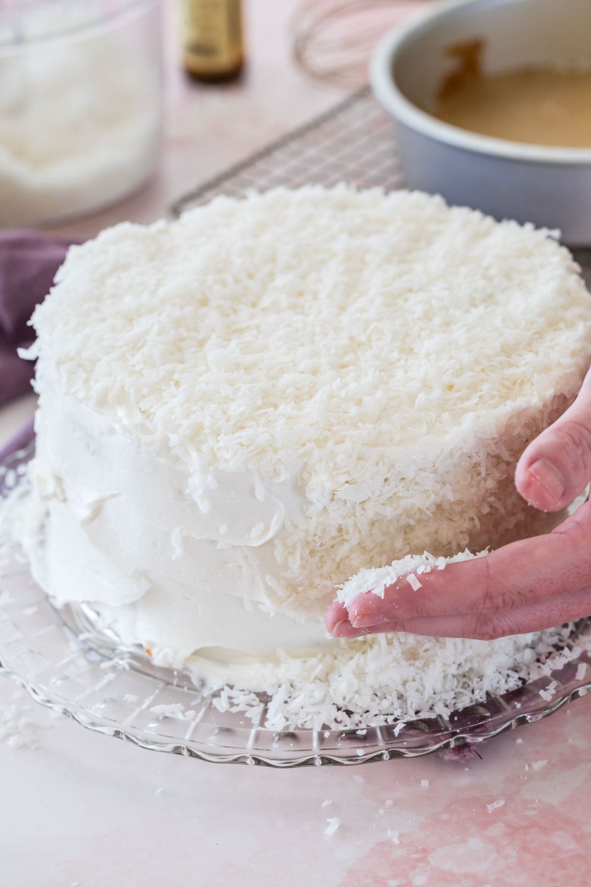 Covering a white-iced cake with shredded coconut