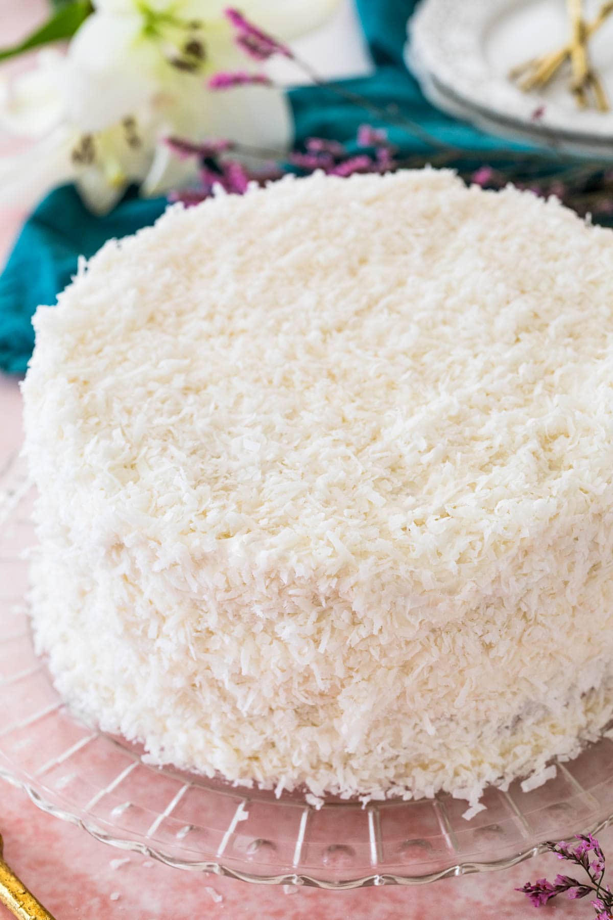 Coconut cake on glass platter, covered with shredded coconut