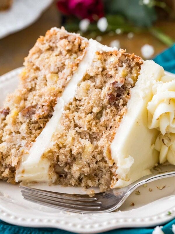 Slice of cream cheese frosted hummingbird cake on a white plate