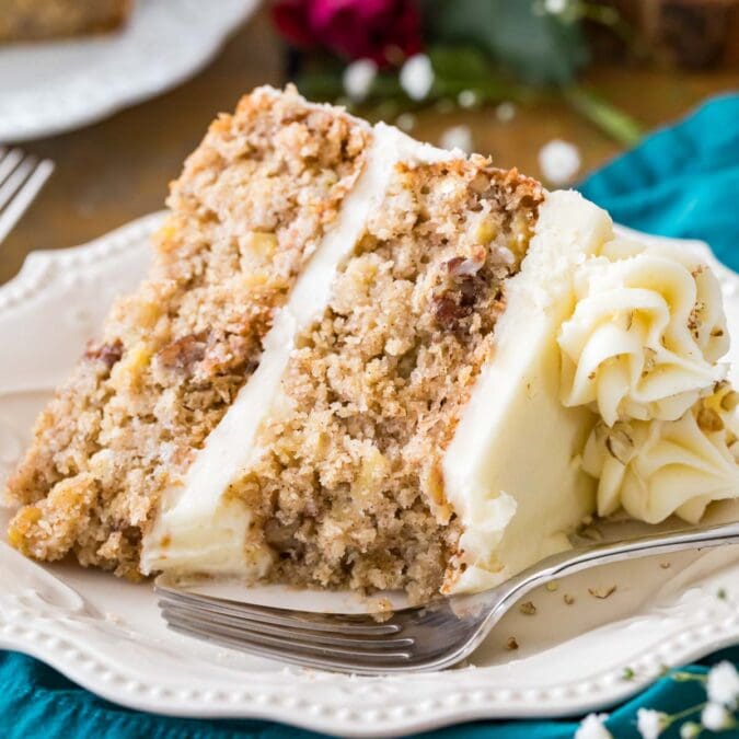 Slice of cream cheese frosted hummingbird cake on a white plate