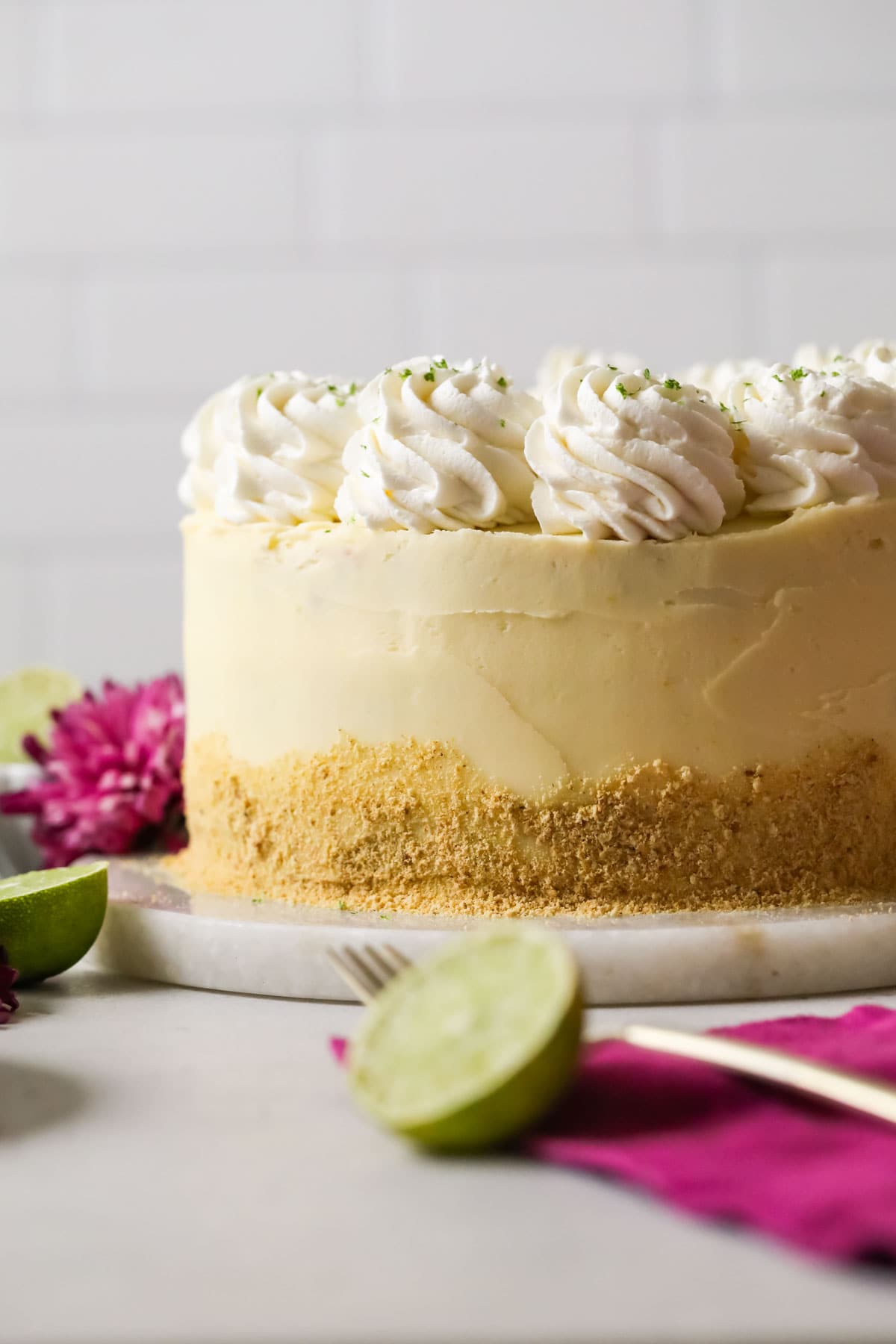Key lime cake that's been decorated with graham cracker crumbs and piped whipped cream swirls.