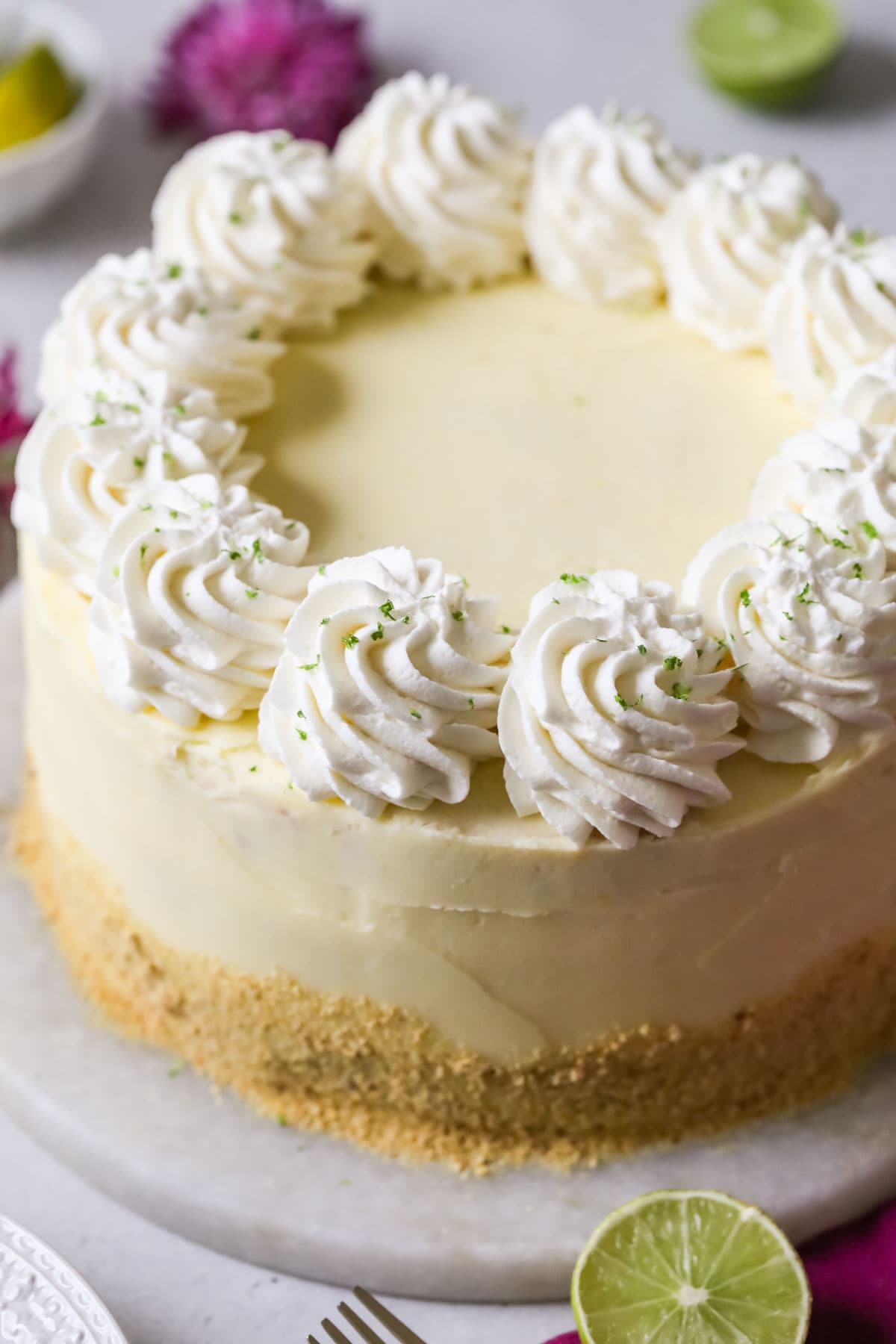 Overhead view of a cake that's been decorated with graham cracker crumbs, whipped cream swirls, and lime zest.