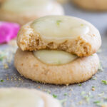 Two key lime cookies stacked on top of each other with the top cookie missing a bite.