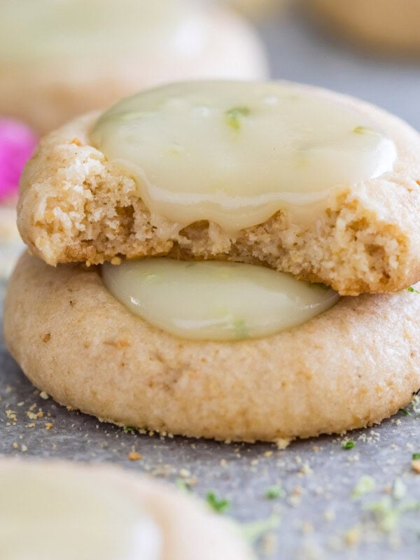 Two key lime cookies stacked on top of each other with the top cookie missing a bite.