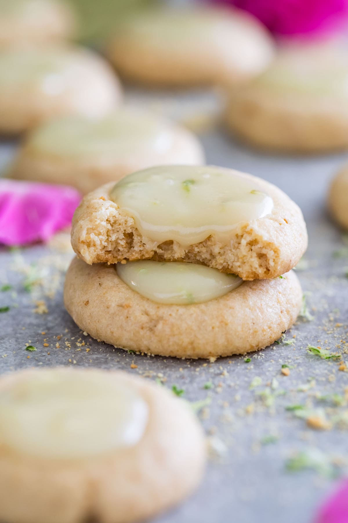 Two key lime cookies stacked on top of each other with the top cookie missing a bite.