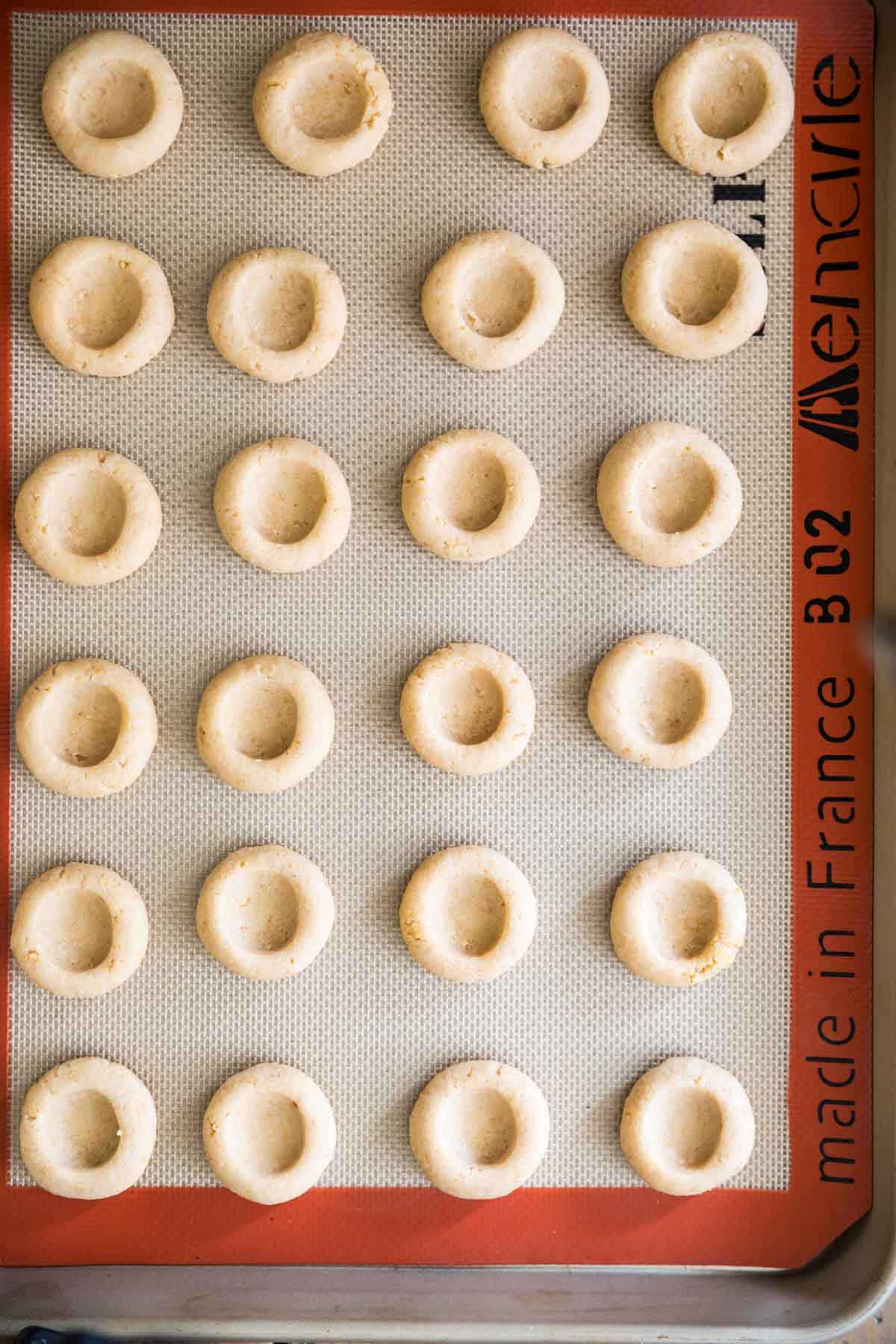Overhead view of thumbprint cookies on a silicone baking mat.