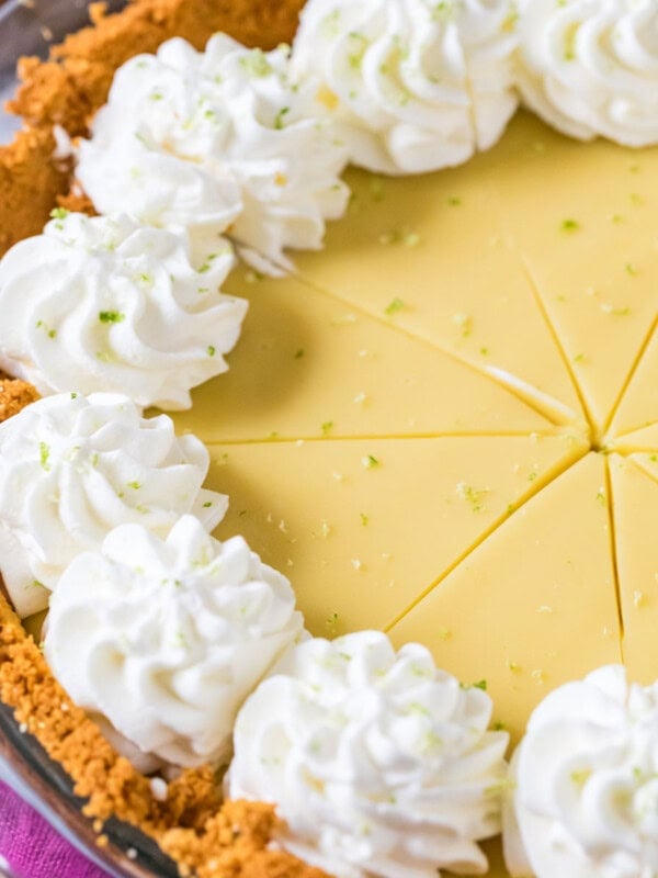 Key lime pie that's been cut into slices and topped with whipped cream swirls.