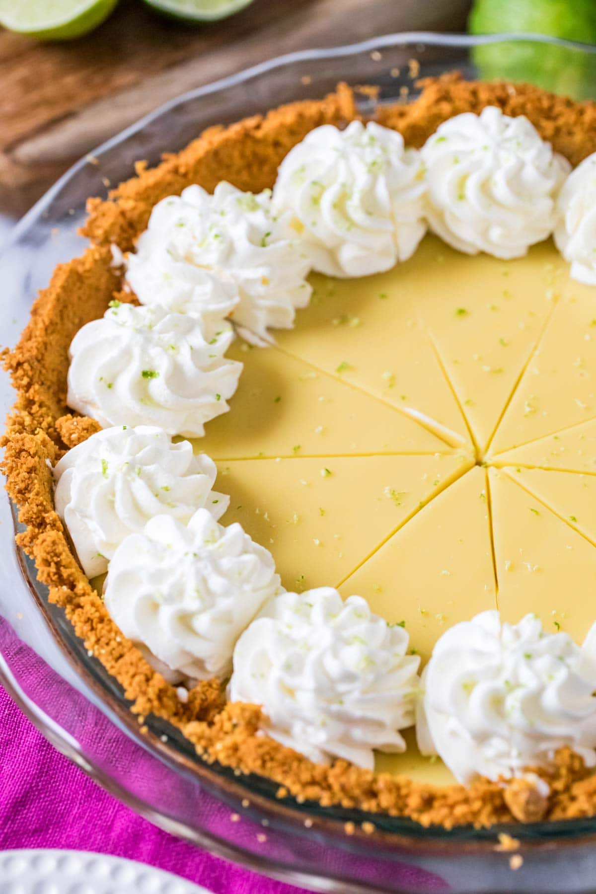 Key lime pie that's been cut into slices and topped with whipped cream swirls.