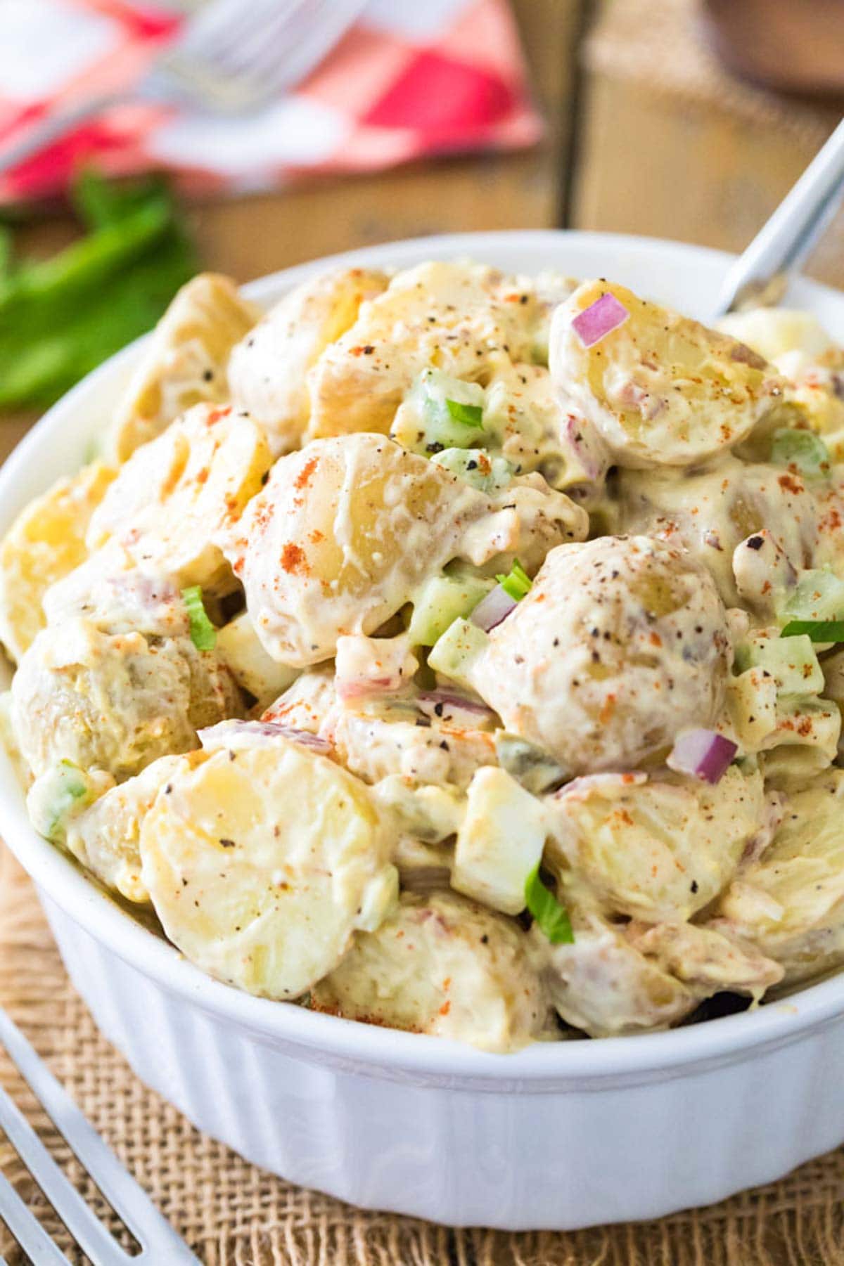 Close-up view of potato salad made with celery, onions, and more in a large white serving bowl.