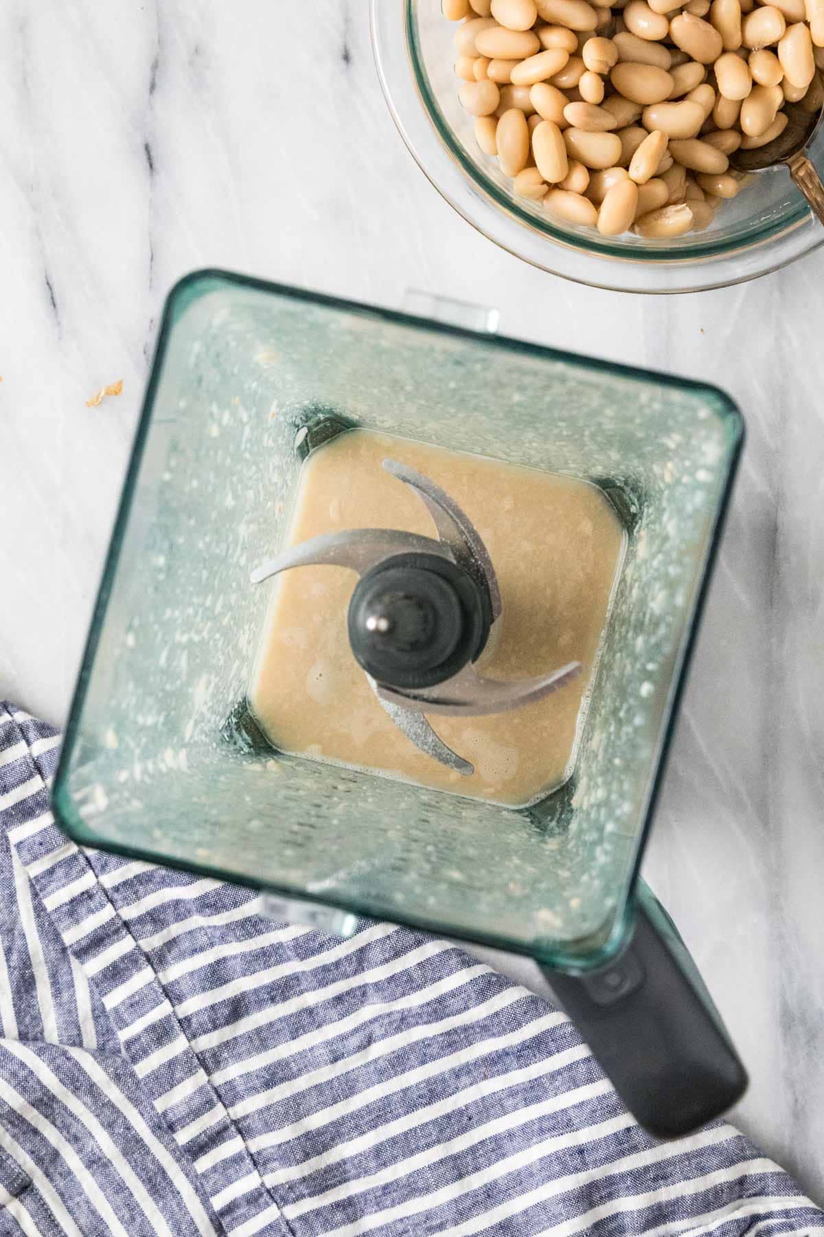 Overhead view of a blender that has combined white beans and chicken broth.