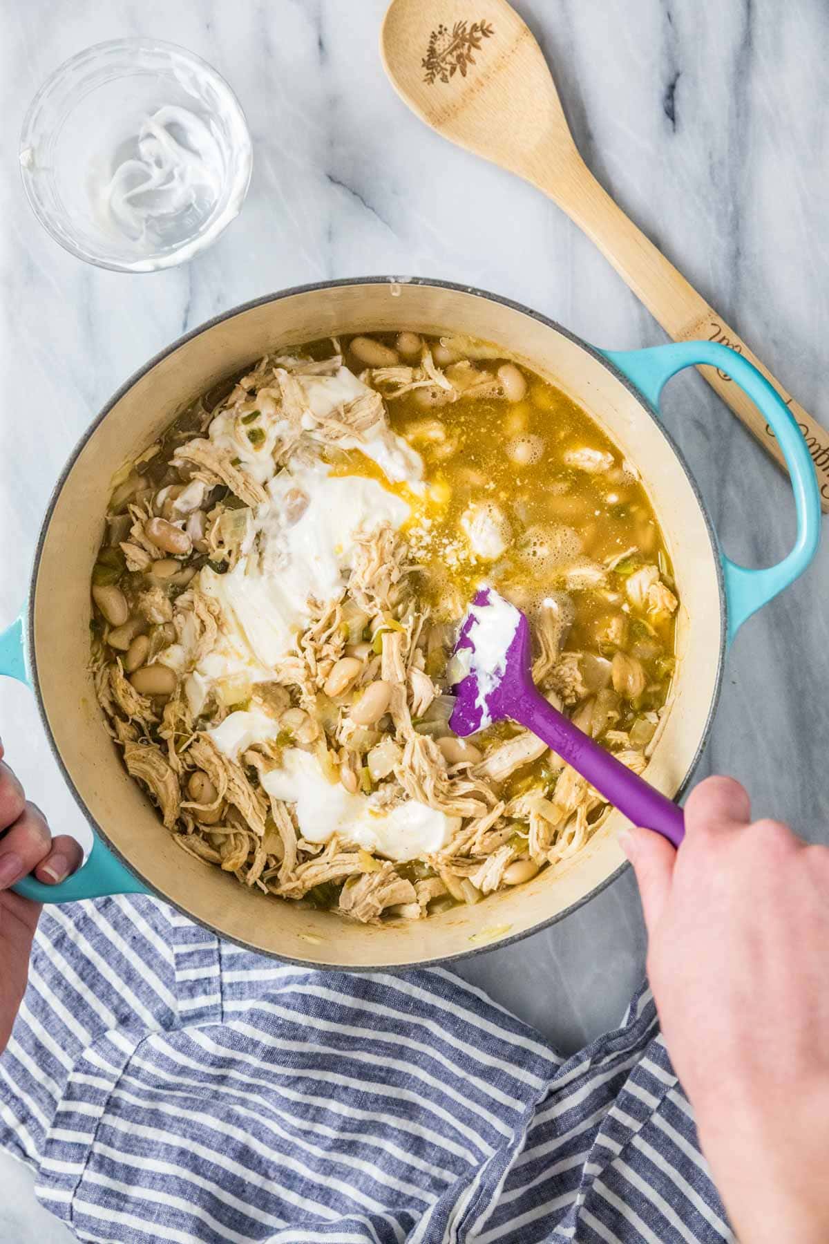 Overhead view of a pot of white chicken chili after adding sour cream.