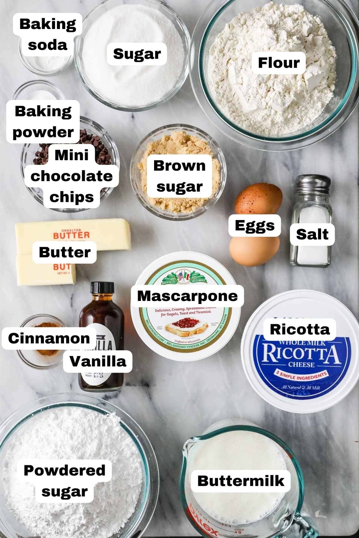 Overhead view of labelled ingredients including mascarpone, ricotta, cinnamon, and more.