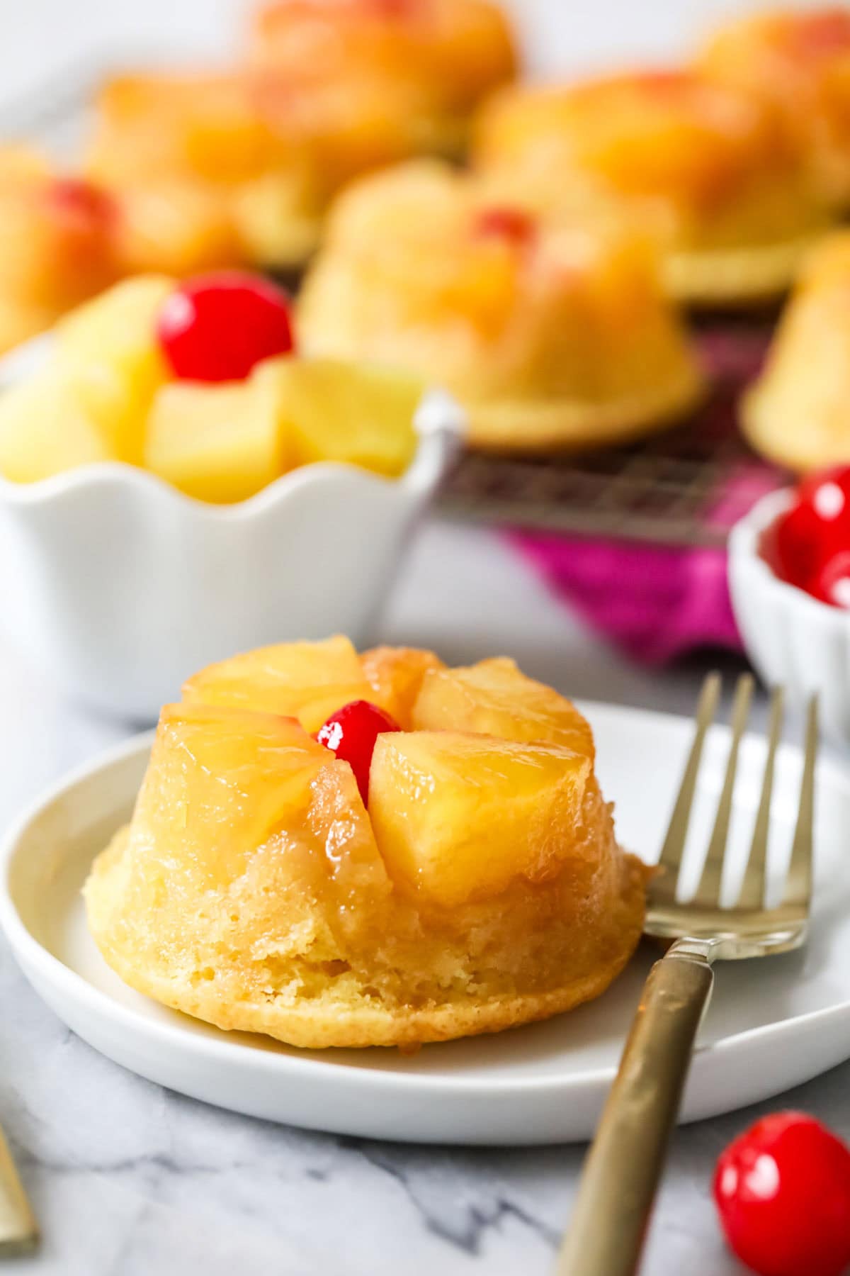 Pineapple upside down cupcake on a plate with a fork.