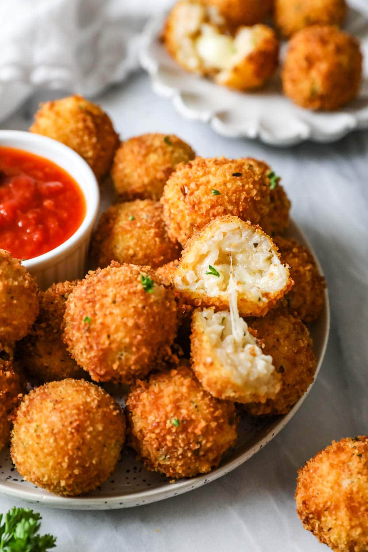 Plate of arancini with one cut in half to show a cheesy filling.
