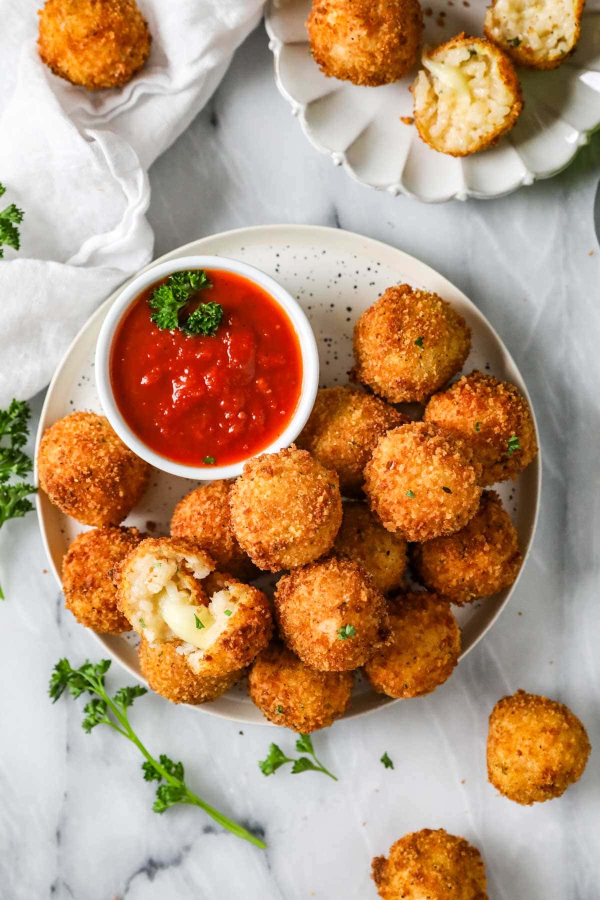 Overhead view of a bowl Sicilian fried rice balls with marinara for dipping.