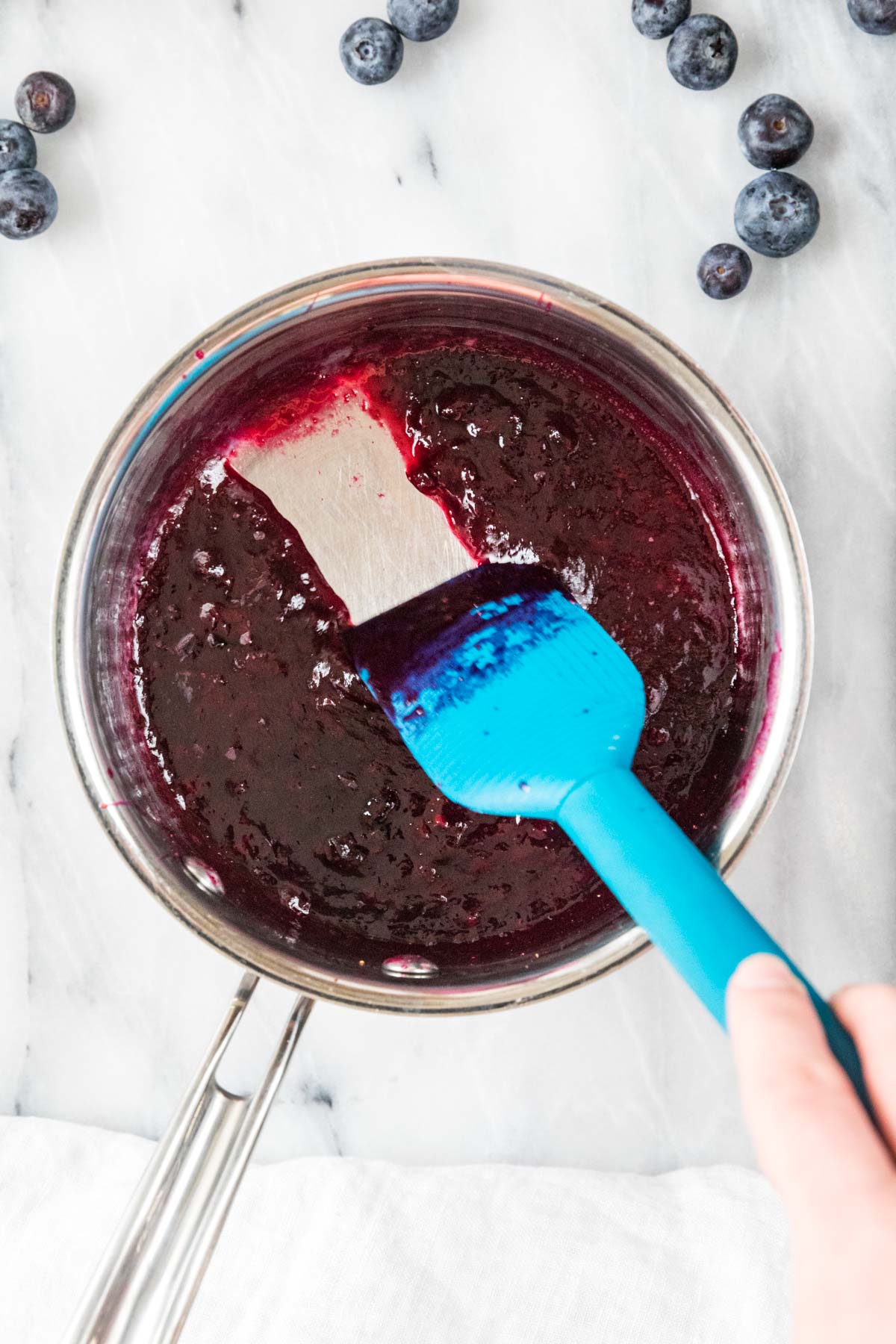 Spatula running through a blueberry sauce with a clear trail.