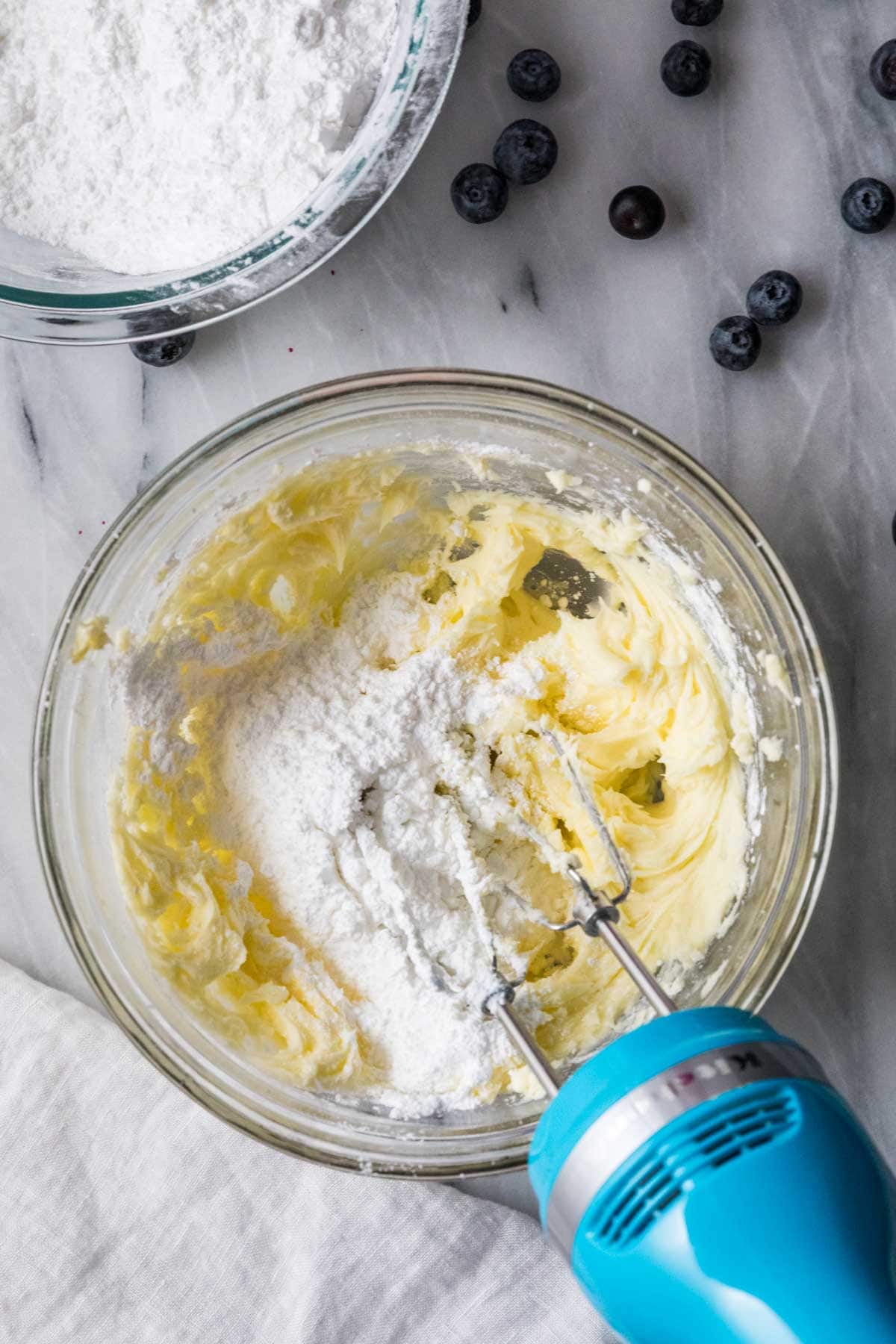 Butter and powdered sugar being combined with an electric mixer.