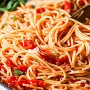 Close-up view of spaghetti tossed with a cherry tomato sauce.