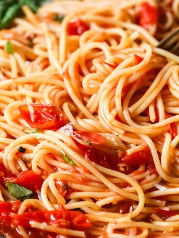 Close-up view of spaghetti tossed with a cherry tomato sauce.