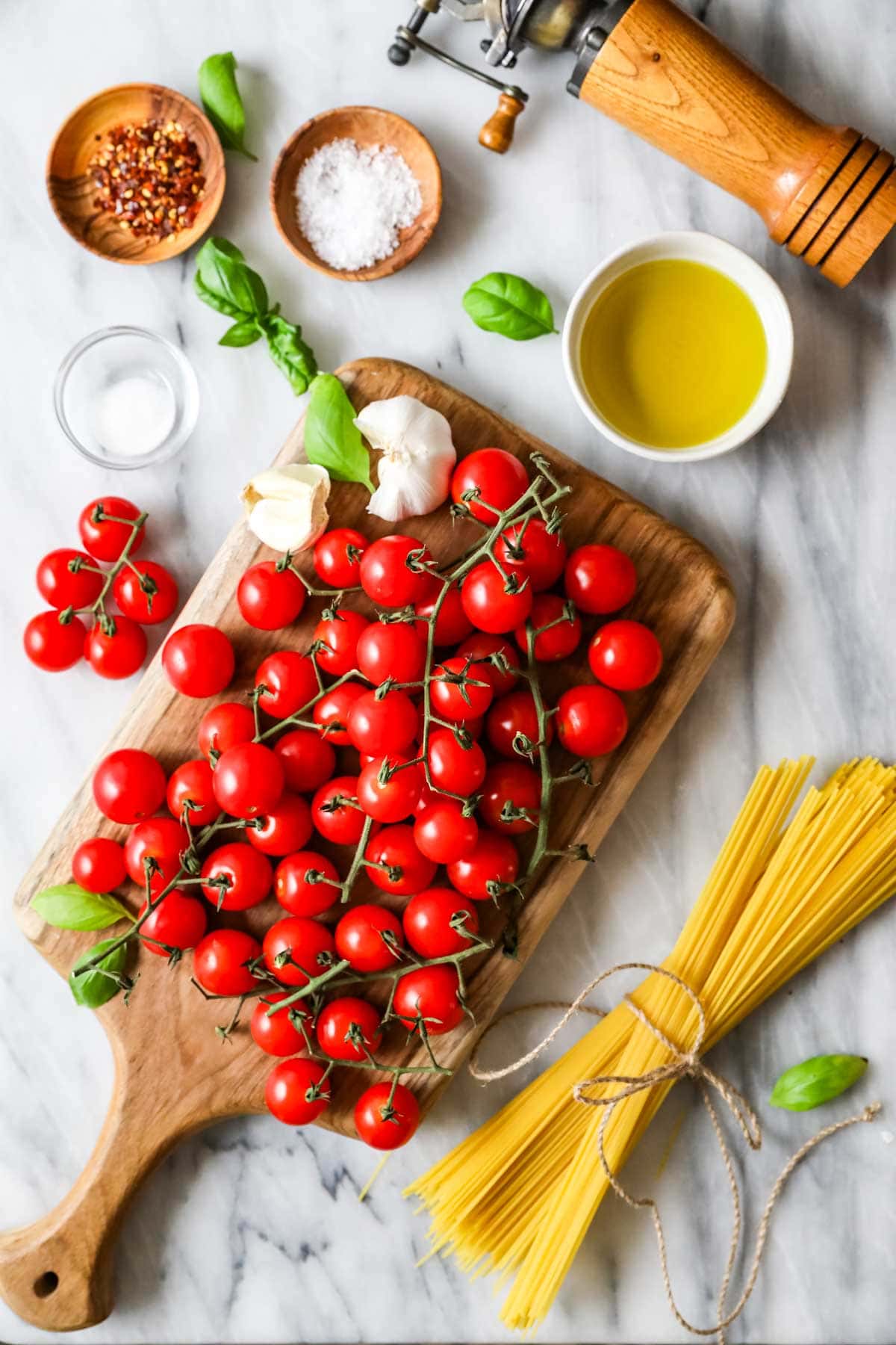 Overhead view of ingredients including cherry tomatoes, olive oil, garlic, and more.