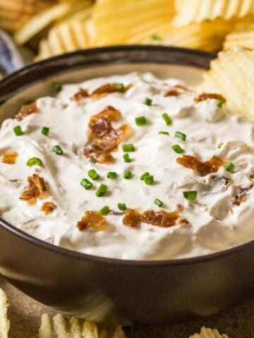Bowl of homemade french onion dip surrounded by ripple chips.