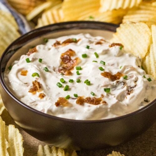 Bowl of homemade french onion dip surrounded by ripple chips.