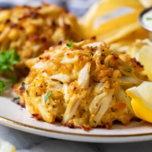 Close-up view of golden brown, Maryland-style crab cakes on a plate.