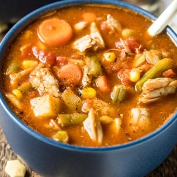 Blue bowl of maryland crab soup made with a tomato base, lump crab meat, old bay, and more.