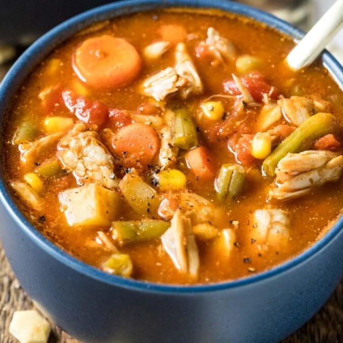 Blue bowl of maryland crab soup made with a tomato base, lump crab meat, old bay, and more.