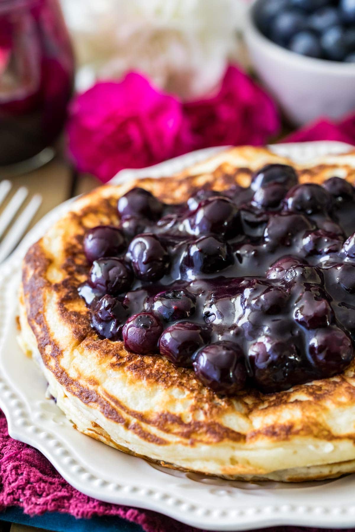 Stack of pancakes topped with a sauce made from blueberries.