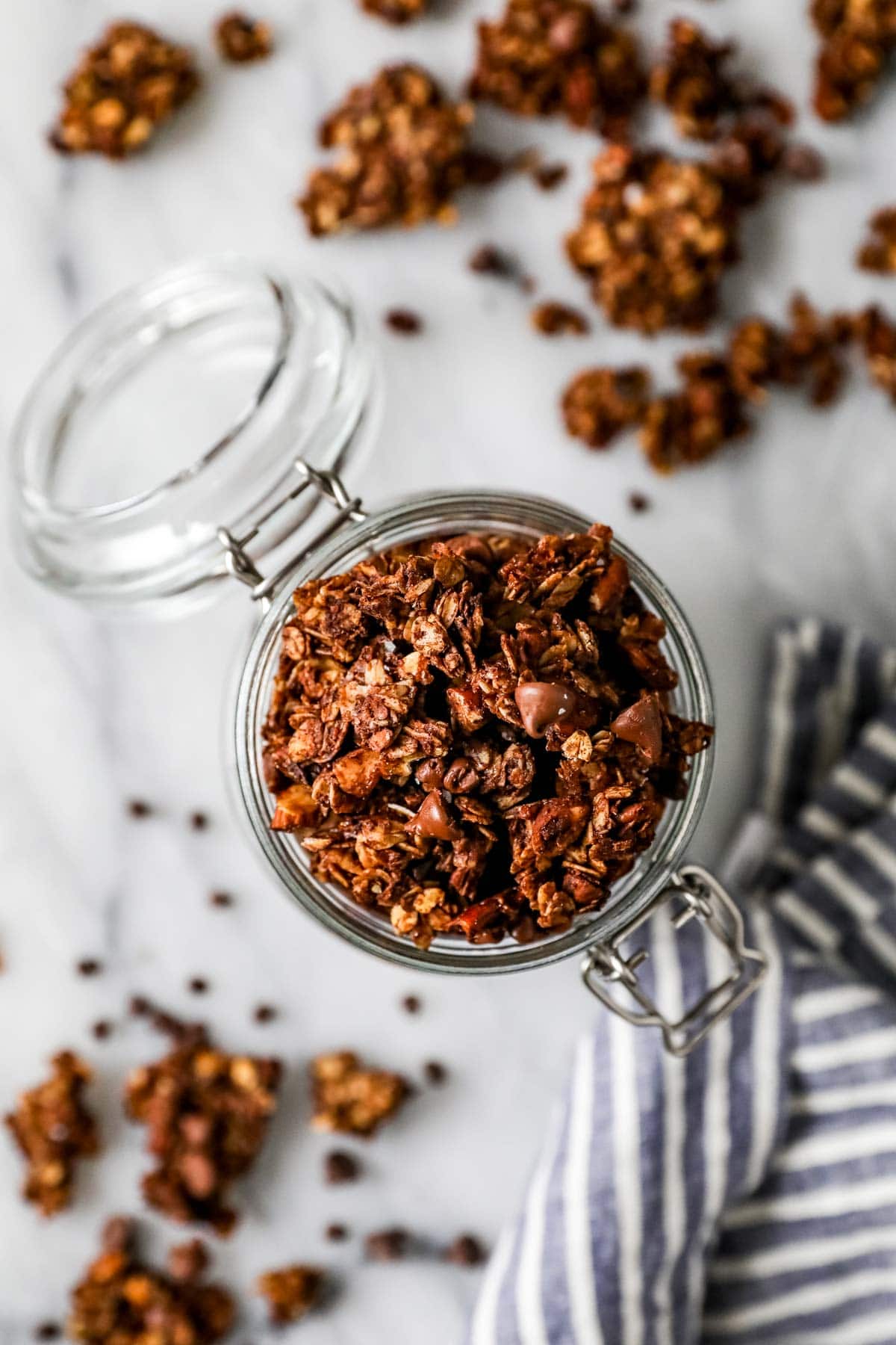 Overhead view of a jar of homemade granola made with cocoa powder, nuts, and more.