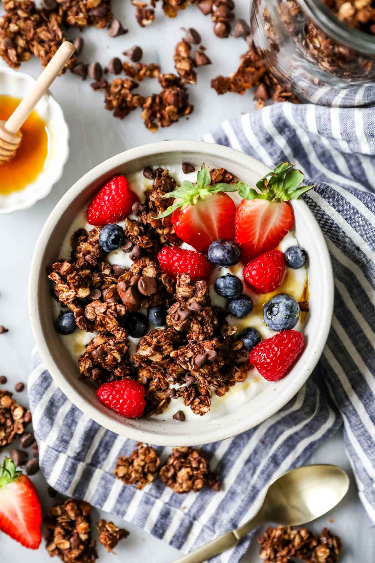 Overhead view of chocolate granola sprinkled over a bowl of yogurt and berries.